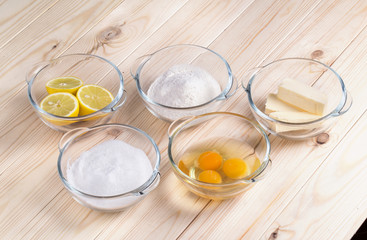 Ingredients for home-grandmother lemon in glass bowls on a table with light wood

