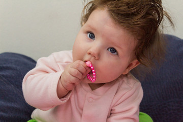 Baby sitting and chewing on the beads.