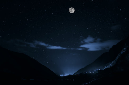 mountain river with stones and grass in the forest at the foot of mountain slope at night in moon light. Azerbaijan