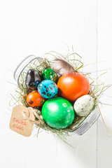 Colourfull Easter eggs in the bucket with hay