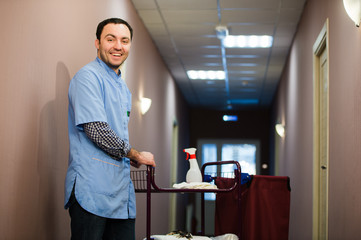 Man cleaning hotel hall wearing blue coat