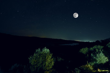Naklejka na ściany i meble Beautiful night landscape of big full moon rising over the mountain road with hill and trees. Forest and mountains of south part of Azerbaijan. Masalli Yardimli