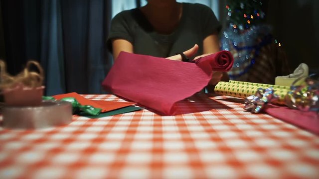 Female cutting pink wrapping paper for packing presents hd