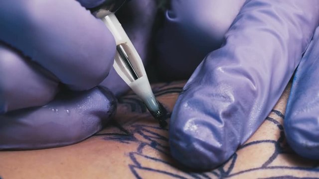 Tattoo master in gloves makes the tattoo close-up