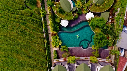 Fototapeten Top view of a model men in light green shorts is enjoying relax in hotel pool. Aerial view. © leo_nik