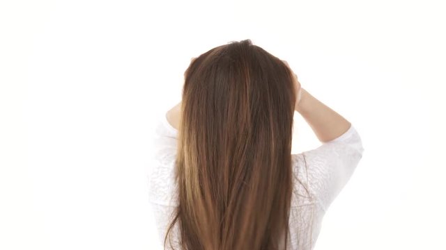 Young woman shaking combing with fingers her healthy hair. Rear view of the young female with beauty straight long brown hairs, studio shot isolated on white background 4K ProRes HQ codec