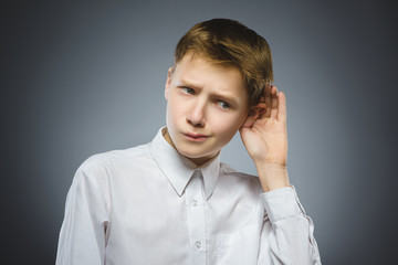 Disappointed boy listens. child hearing something, hand to ear gesture
