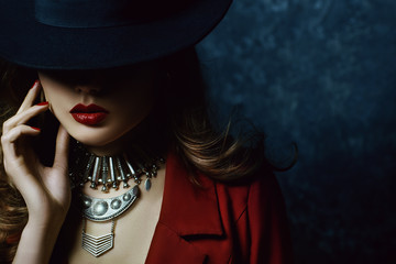 Indoor portrait of a young beautiful  fashionable woman wearing stylish accessories. Hidden eyes with hat. Female fashion, beauty and advertisement concept. Close up. Copy space for text - obrazy, fototapety, plakaty