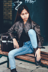 Fototapeta na wymiar Gorgeous girl in leather jacket posing on the bench