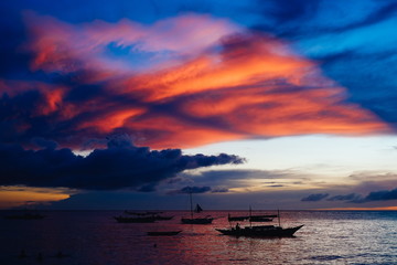 Fototapeta na wymiar Beautiful, colorful sunset over fishing boats and people in water