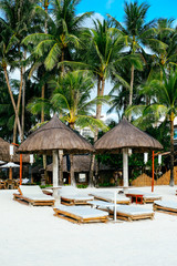 Nipa hut sun shade with two bamboo sunbeds on white coral sand beach