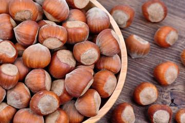 Many hazelnuts in a bamboo bowl on table