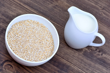 Oat in a ceramic bowl and pitcher with milk