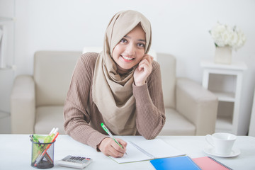 beautiful female asian student with hijab doing homework