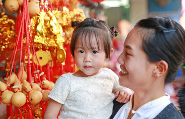 Asian woman and her daughter in Chinese dress against traditional chinese red decorations are very popular during the Chinese new year Festival at chinatown in bangkok, Thailand.