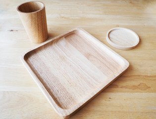 Wooden square plate and round saucer with glass on wood background