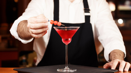 Barman in making cocktail at a nightclub. Nightlife concept. No face. Decorating drink