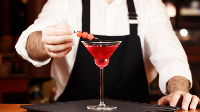 Barman in making cocktail at a nightclub. Nightlife concept. No face. Decorating drink