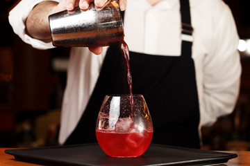 Barman in making cocktail at a nightclub. Nightlife concept. No face. Pouring into glass