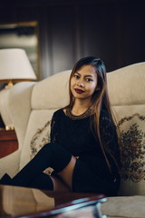 Fototapeta premium Elegant young beautiful woman in gorgeous silk dress sitting in antique armchair