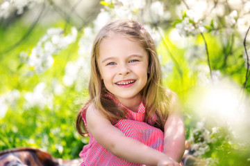 Happy little girl playing in spring cherry garden