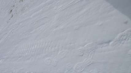 Tire tread and boot tracks on a snow packed road