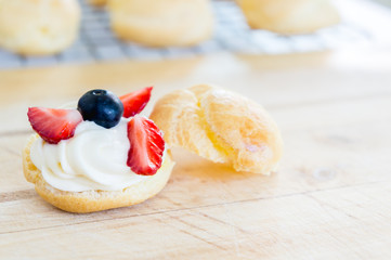 Homemade, Homemade cake, Choux Cream with fresh blueberry and strawberry decorated on wooden background at house.
