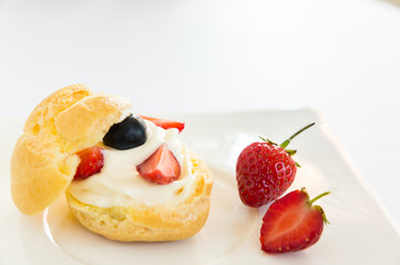 Homemade, Homemade cake, Choux Cream with fresh blueberry and strawberry decorated on white background at house.