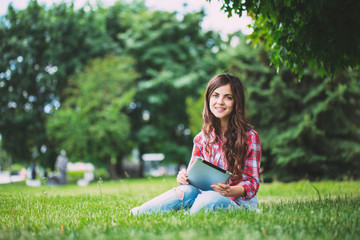 Naklejka na ściany i meble Young beautiful smiling woman with touchpad on outdoors.