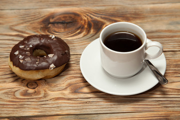 Cup with coffee and donuts on a wooden background