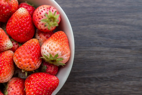 Fresh strawberry in cup on wooden background.