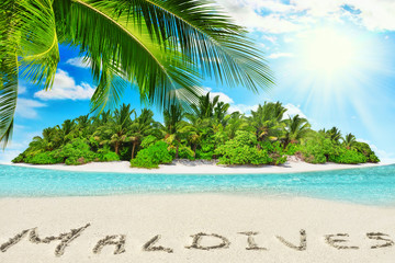 Whole tropical island within atoll in tropical Ocean and inscription "Maldives" in the sand on a tropical island,  Maldives.