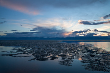Drifting ice formations on water surface and beautiful clouds on sunset © Aniland