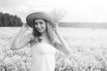 monochrome portrait of young girl in a hat standing in a huge field of flowers