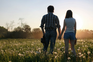 couple of young people walking in the sunset spring evening in a field © alexkich