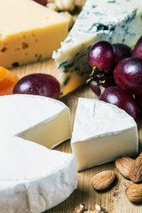 assorted cheeses, nuts and grapes on a wooden table