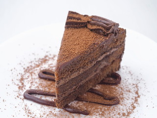 Piece of chocolate cake isolated on white plate. Slice of fresh brownie.  Copy space for your text. Selective focus on the front.