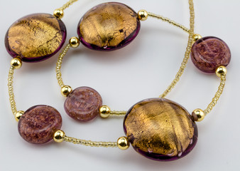 Glass - Murano gold bead necklace close up on white background