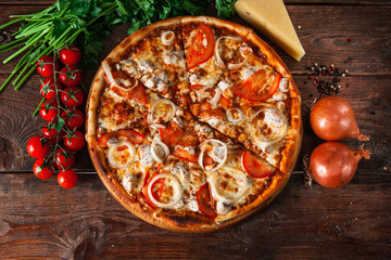 Traditional italian food. Delicious fresh pizza with tomatoes, chicken and onion on wooden...