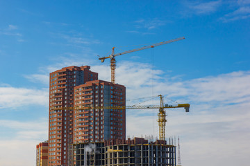 Crane and building construction site against blue sky.