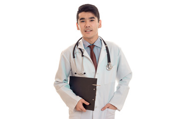 portrait of serious young brunette male doctor in uniform with stethoscope posing isolated on white background