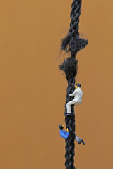 切れそうなロープを登るビジネスマン