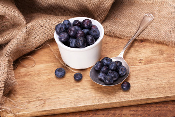 Pot of blueberries with spoon on a rustic background