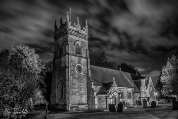 A country village church in the UK taken in black and white mono taken at night from the graveyard