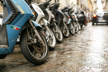 Scooters parked along cobblestone street in Florence, Italy.
