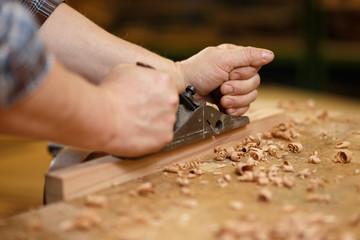 Carpenter working with planer on the workbench
