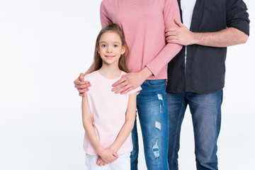 Cropped shot of young family with one child standing together on white