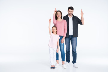 Obraz premium Happy young family standing together and pointing up with fingers