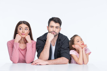 Pensive young family with one child looking at camera on white