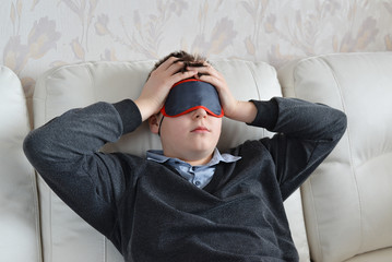 Obraz premium A teenager with a headache in mask for sleep